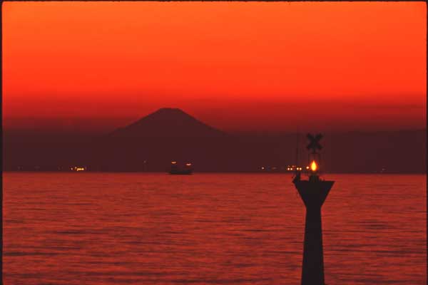 南房総からの帰り道、アクアラインを走行中に富士山が見えました。休憩も兼ねて海ほたるへ寄りましたが、わずかな差で夕陽は見ることはできませんでした。しばらくすると、赤く染まった空と海にシルエットになった富士山が浮かび上がりました。 / 飯田利男　（株）ＩＨＩエスキューブ［関東TUG］